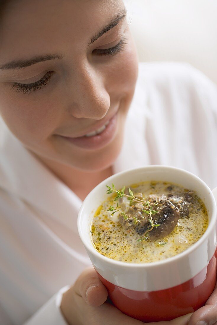 Woman holding cup of mushroom sauce