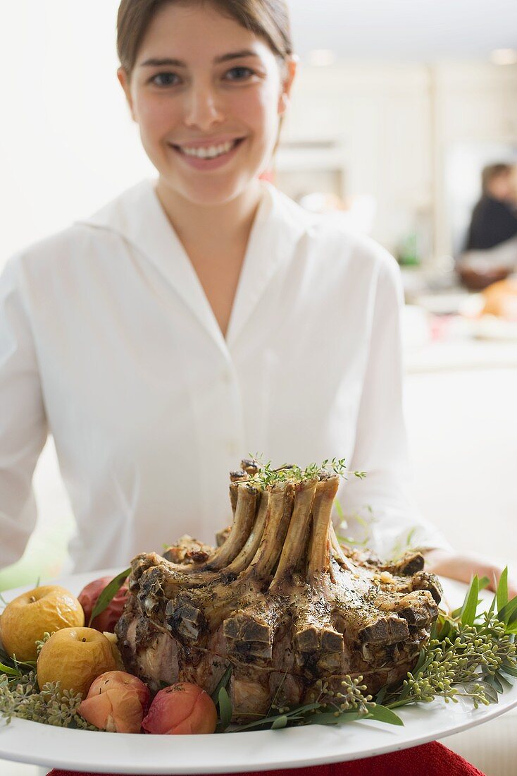 Young woman serving rack of pork for Christmas