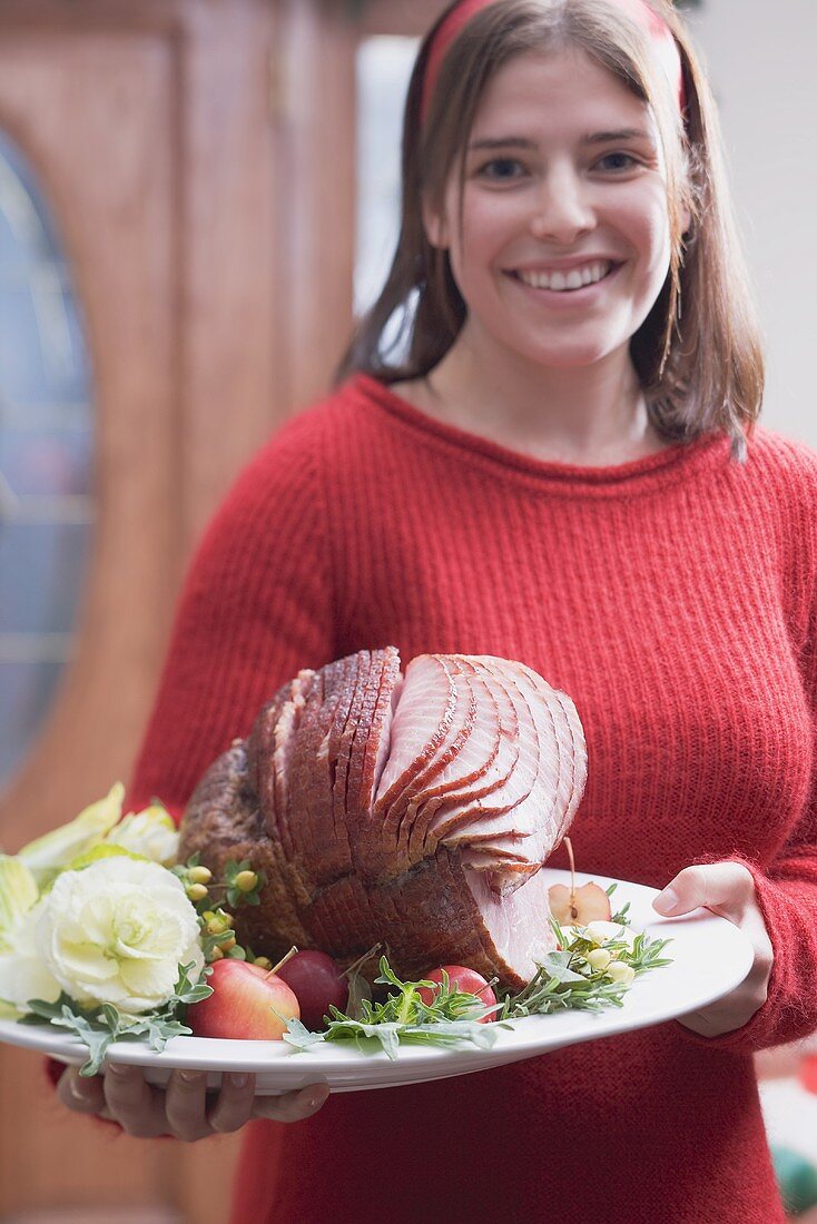 Young woman serving roast ham (Christmas)