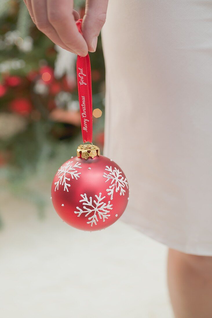 Frau hält rote Christbaumkugel