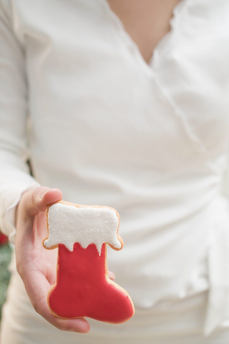 Frau hält Weihnachtsplätzchen (roter Stiefel)