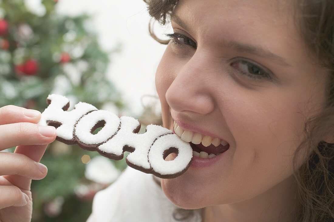Woman biting Christmas biscuit (the word HOHO)