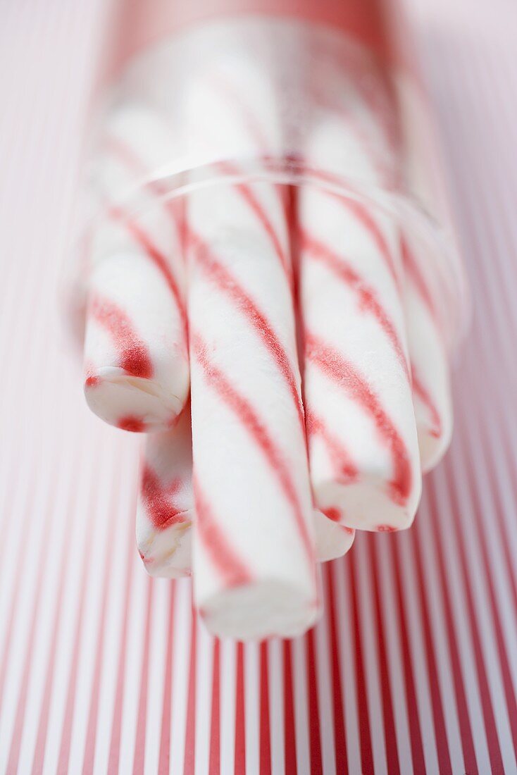 Candy canes in container on striped background