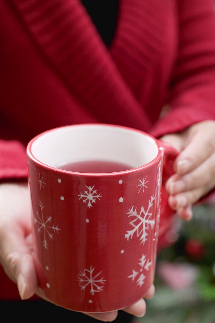 Frau hält weihnachtliche Teetasse
