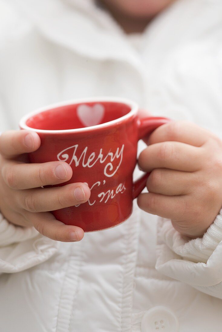 Kind hält weihnachtliche Tasse