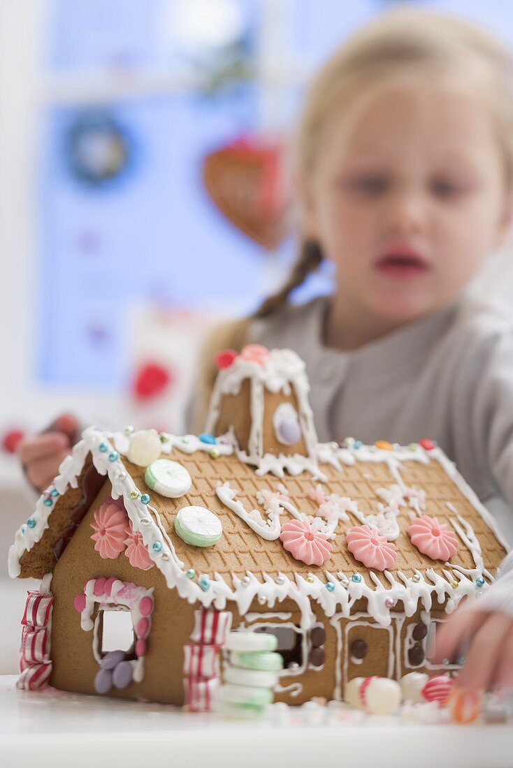 Kleines Mädchen verziert Lebkuchenhaus