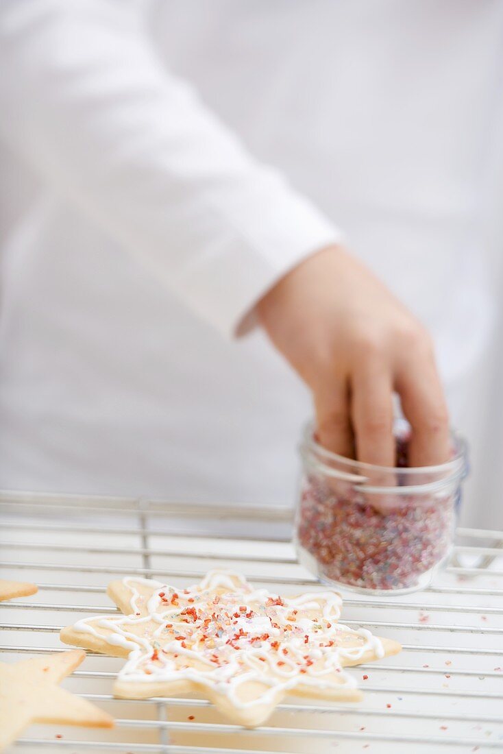 Child decorating Christmas biscuit with sprinkles