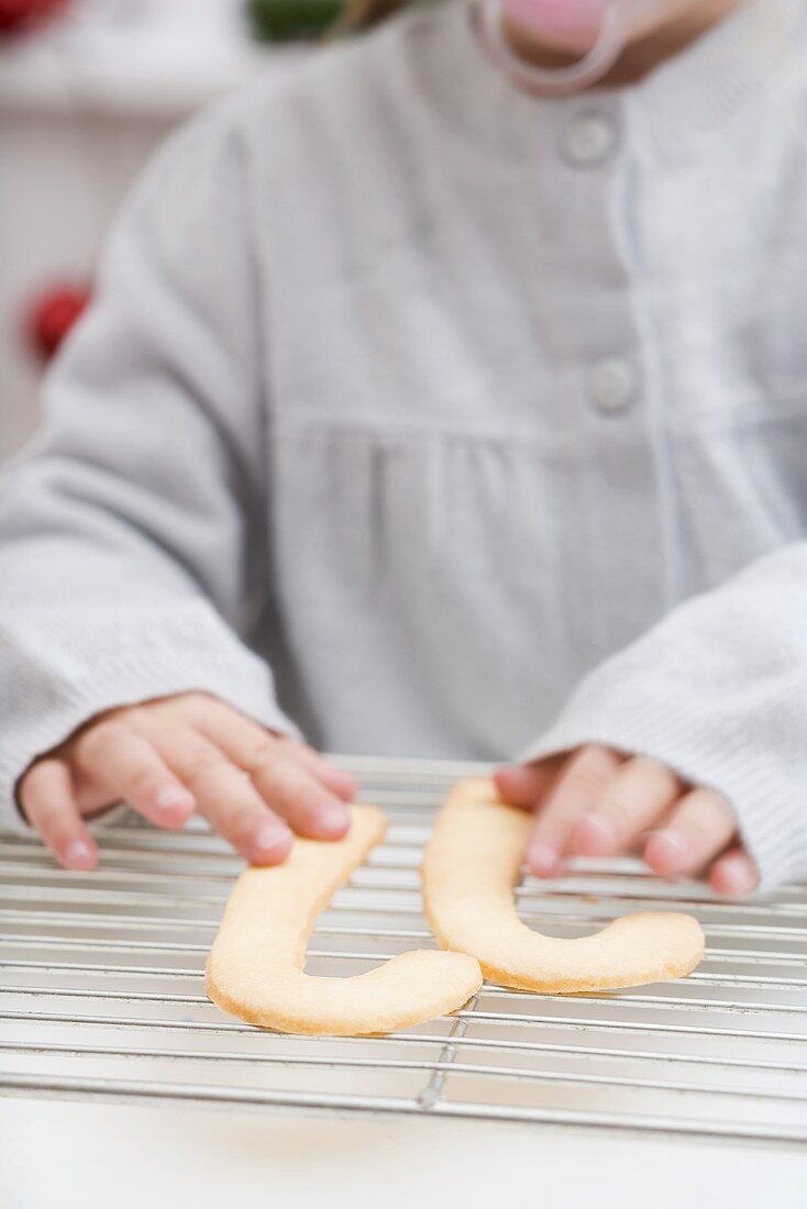 Child reaching for candy cane biscuits on cake rack