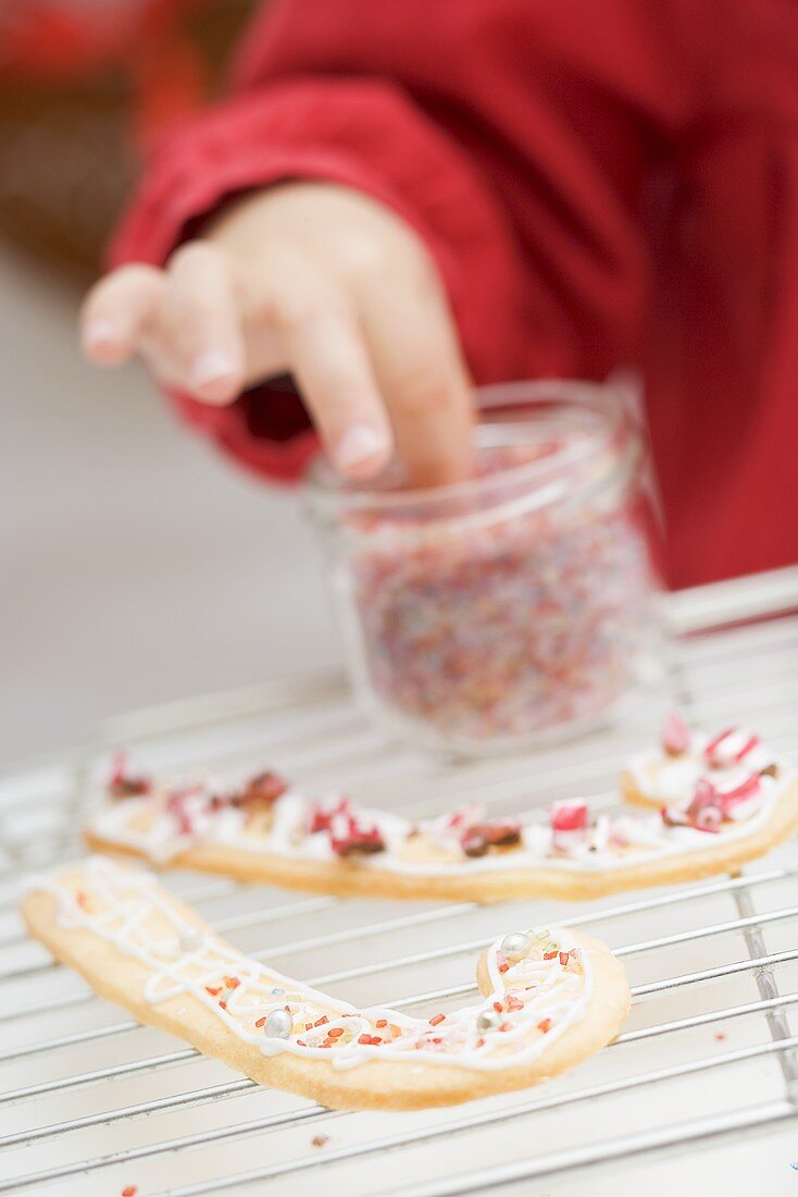 Child decorating Christmas biscuits with sprinkles