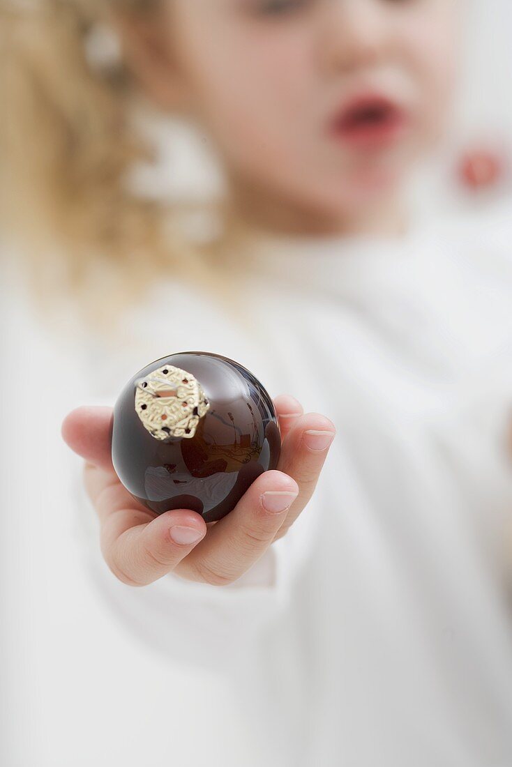 Kleines Mädchen hält Christbaumkugel