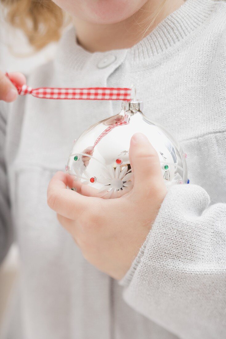 Kleines Mädchen hält Christbaumkugel