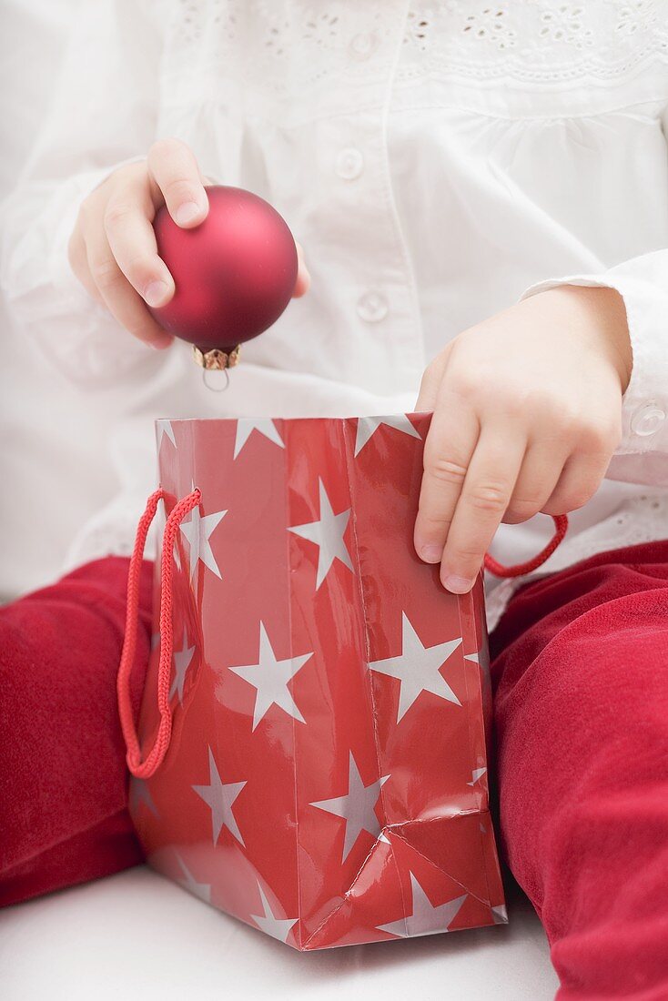 Child taking Christmas bauble out of carrier bag
