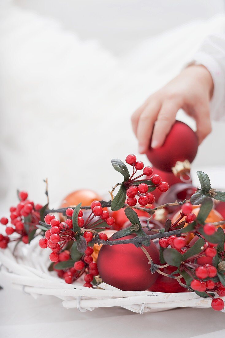 Child placing Christmas bauble in decorated basket