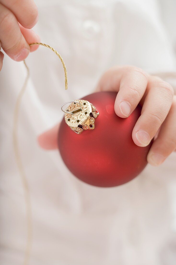 Kind fädelt Schnur durch Christbaumkugel