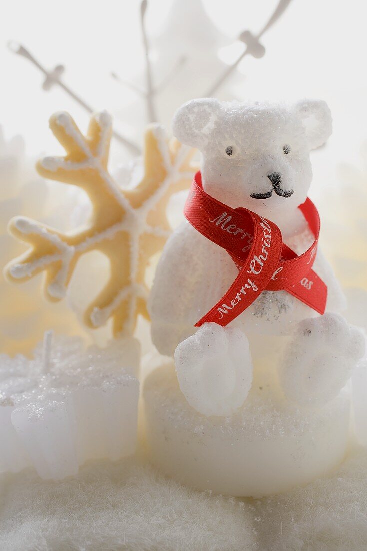 Polar bear candle with ribbon, snowflake biscuit behind