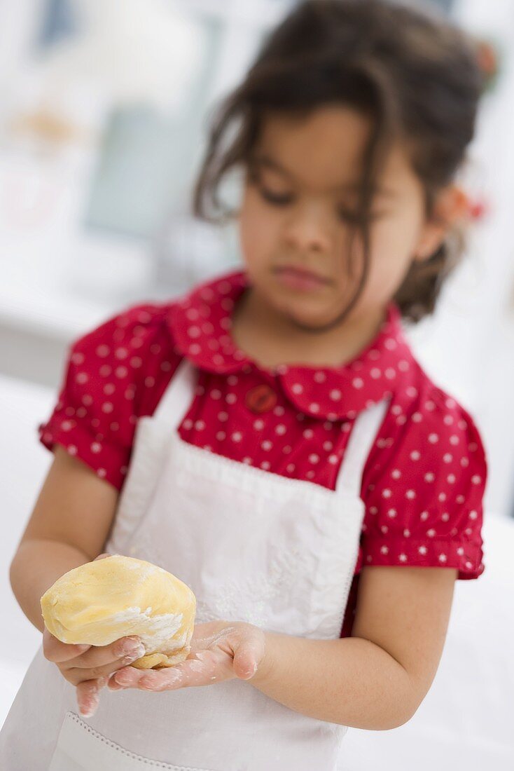 Small girl forming dough into a ball