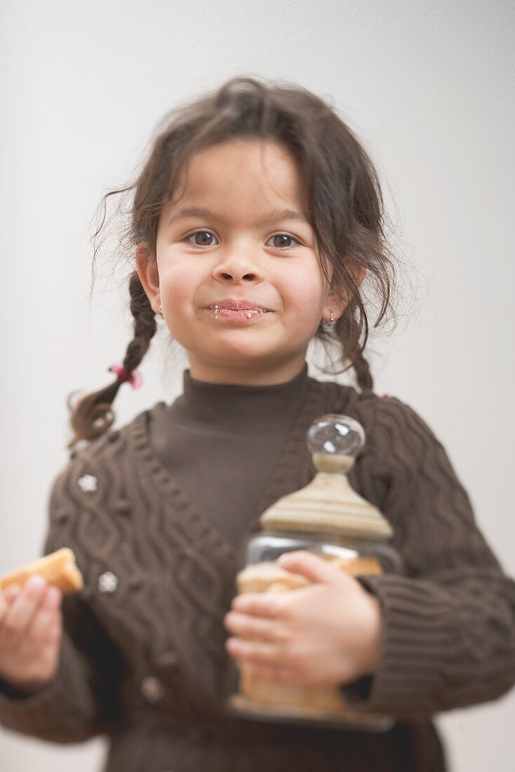 Small girl holding storage jar full of shortbread