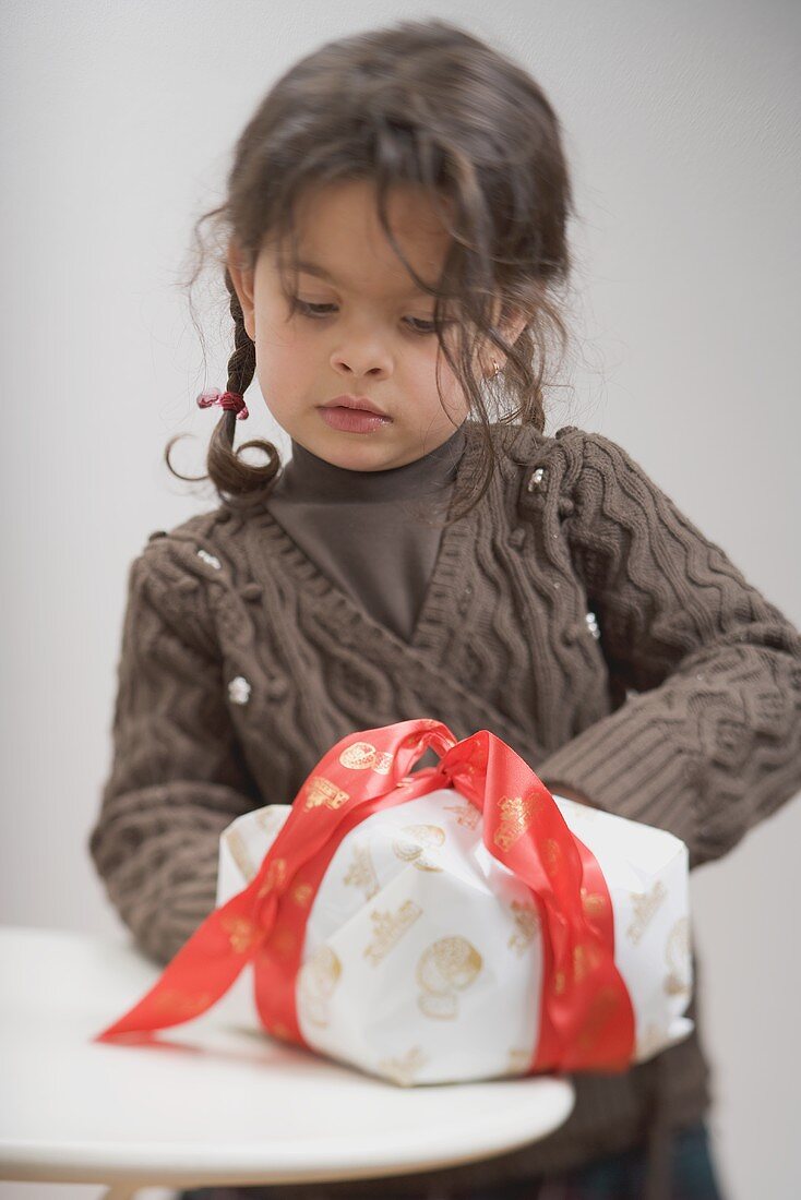 Kleines Mädchen mit weihnachtlich verpacktem Kuchen