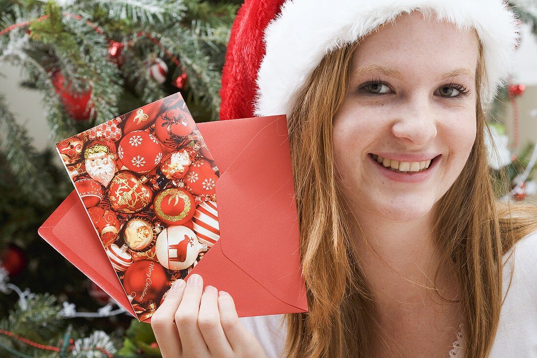 Frau mit Nikolausmütze hält Weihnachtskarte mit Kuvert
