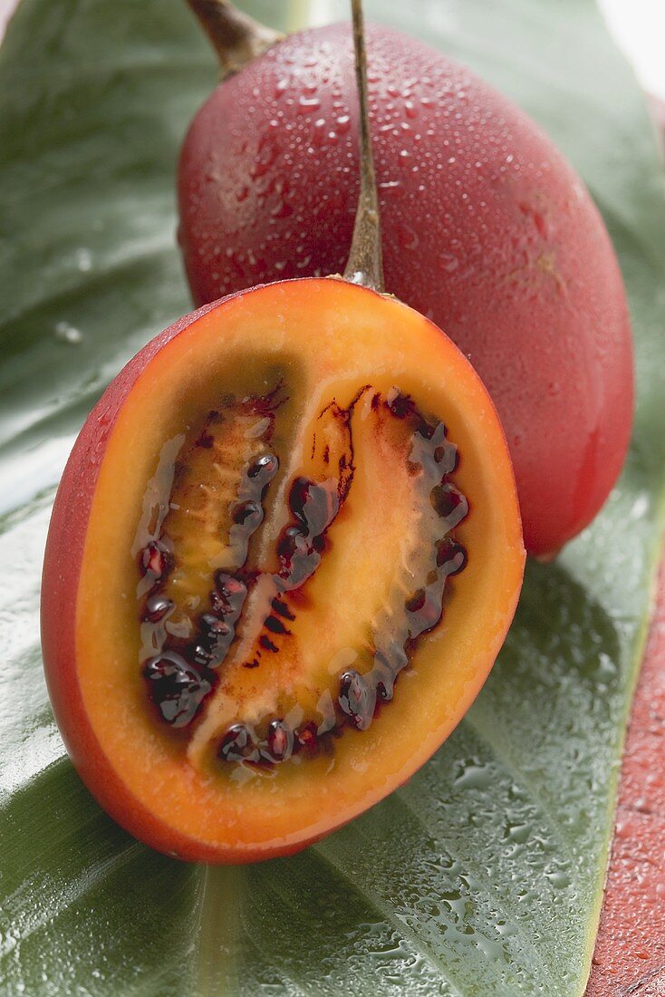 Whole tamarillo and half a tamarillo with drops of water