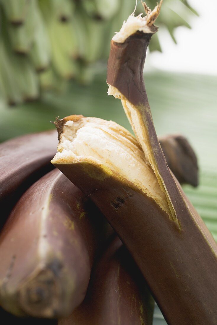 Rote Bananen, eine halb geschält