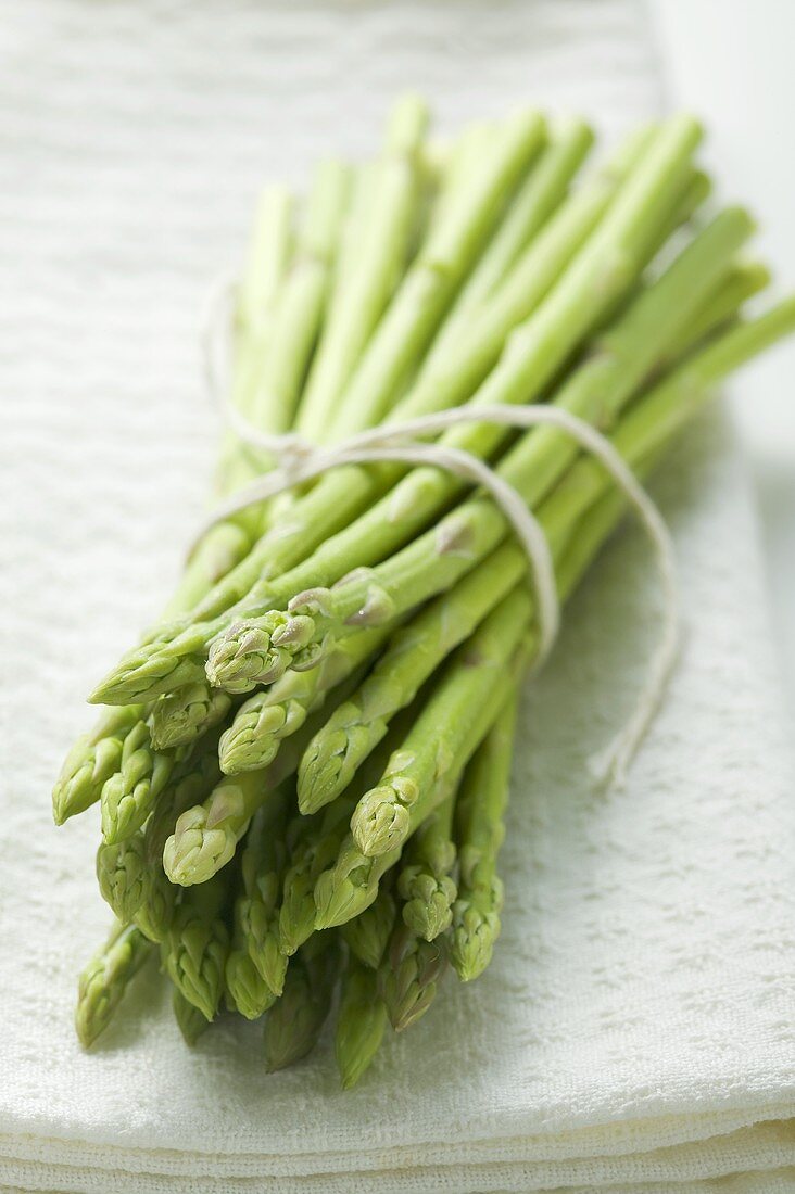 A bundle of green asparagus on white cloth