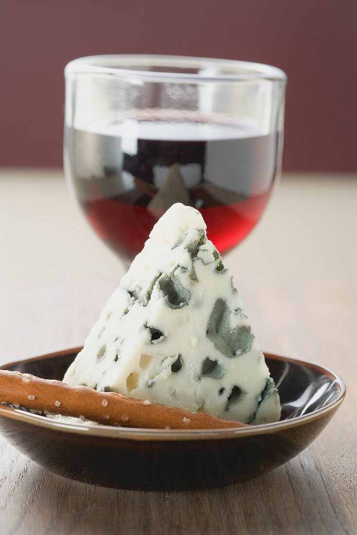 Piece of blue cheese, savoury snack and glass of red wine
