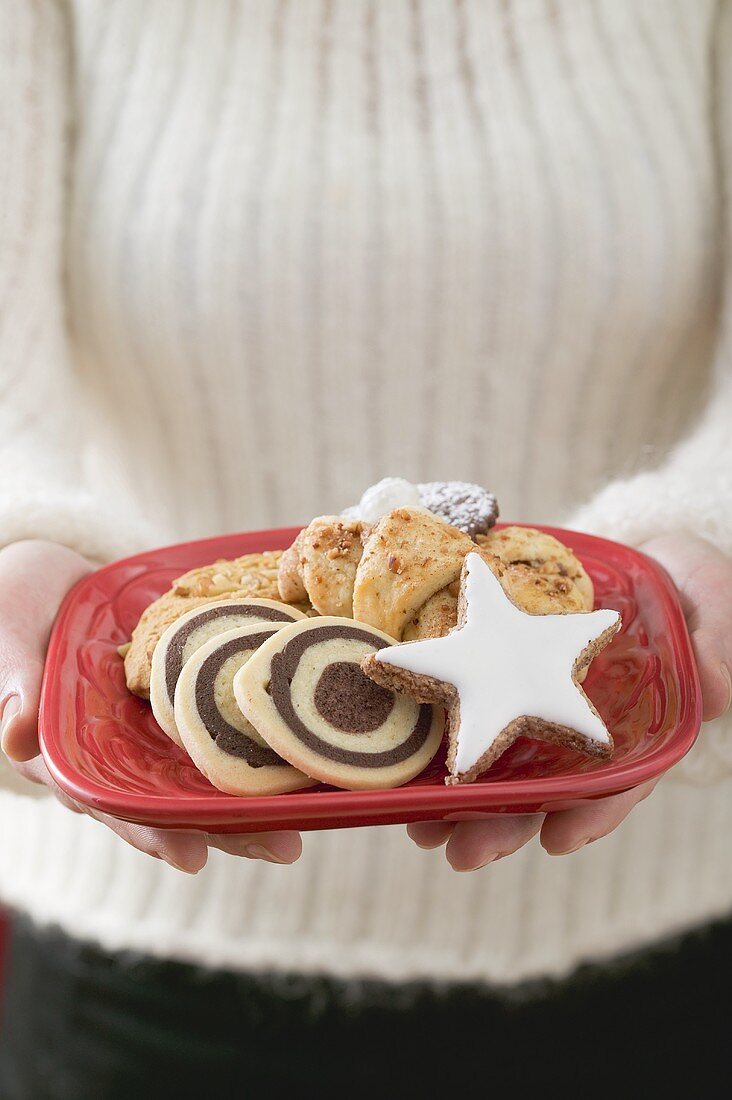 Woman holding plate of Christmas biscuits