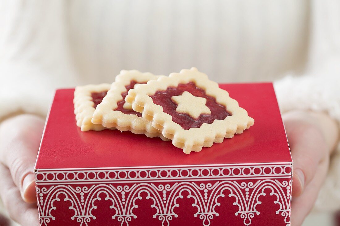 Frau hält Marmeladenplätzchen auf roter Schachtel