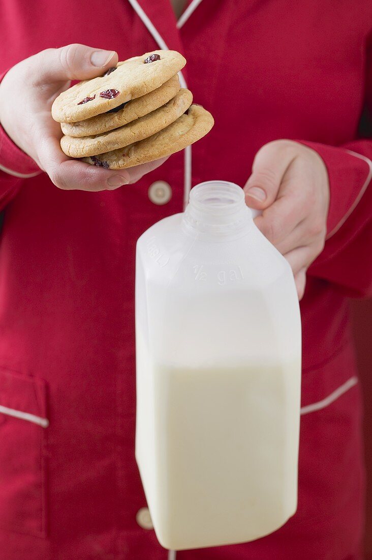 Frau hält Cranberrycookies und Flasche Milch