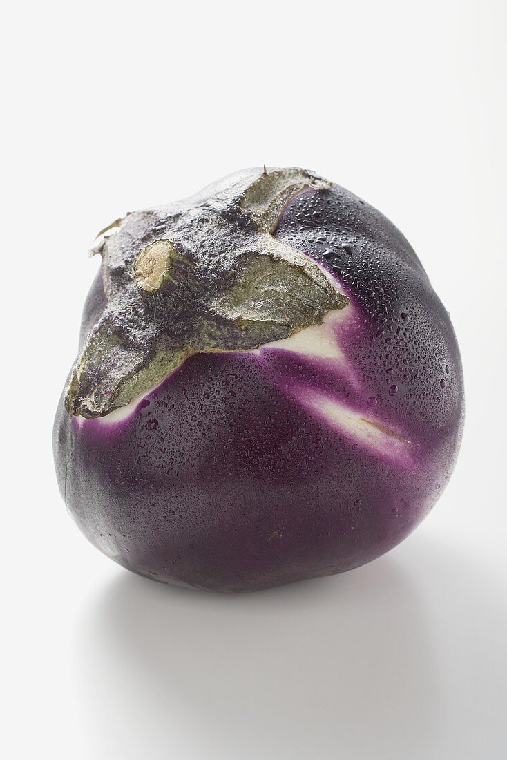 A round aubergine with drops of water