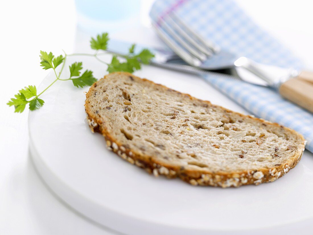 A slice of granary bread with chervil and cutlery