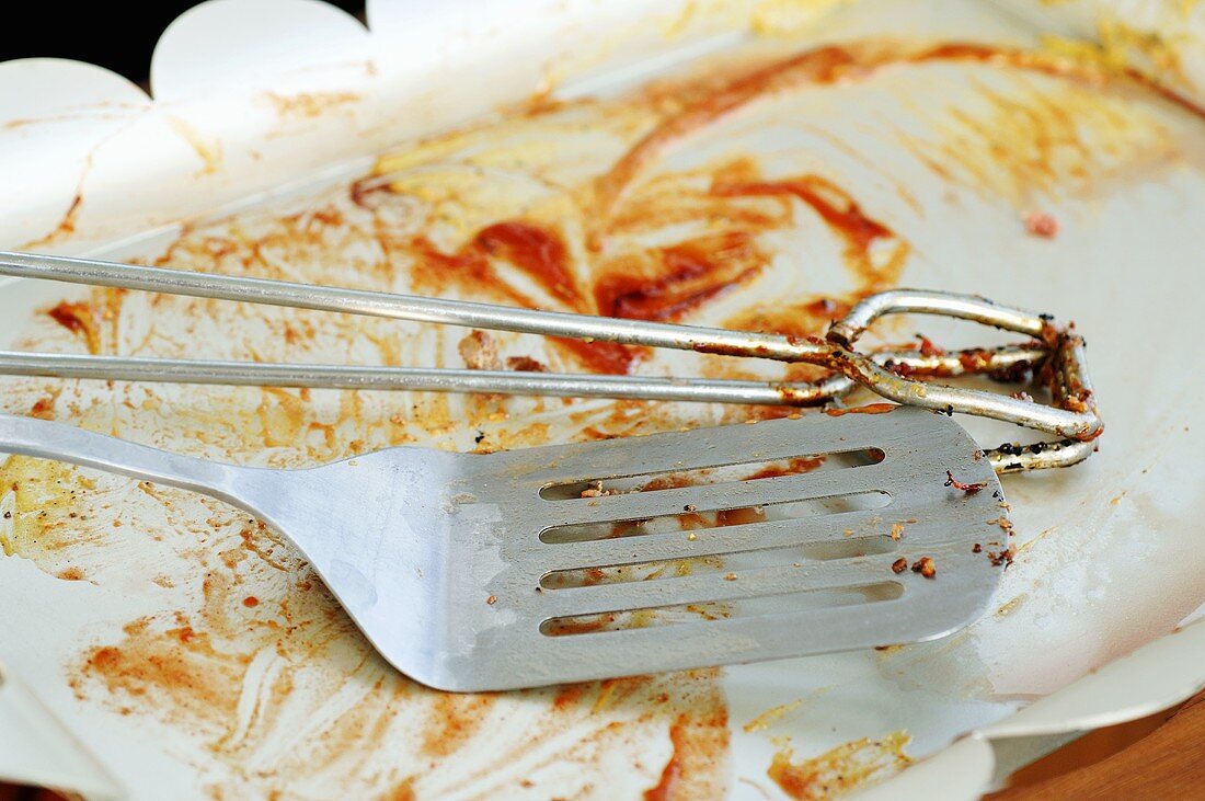 Grill tongs and spatula on plate after grilling