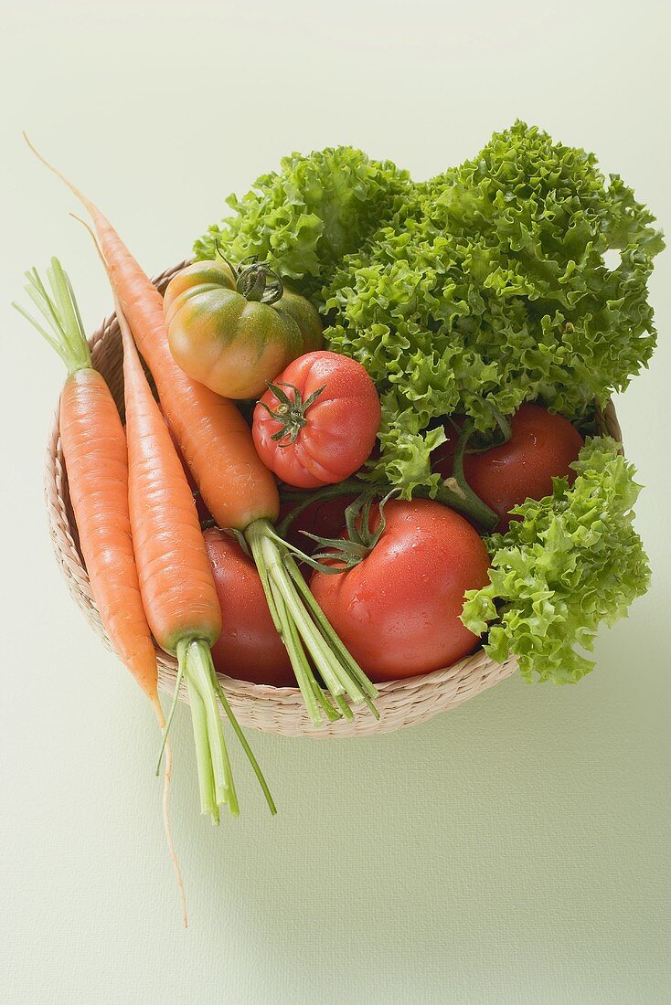 Fresh tomatoes, carrots and lettuce in small basket