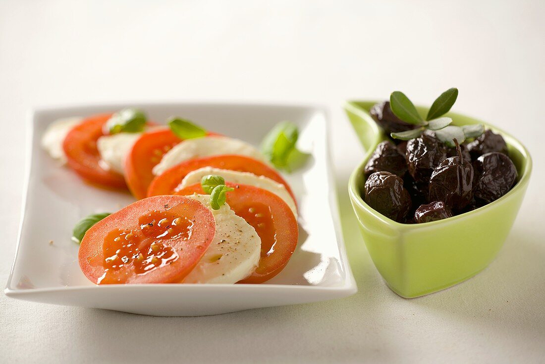 Tomatoes with mozzarella and basil and black olives