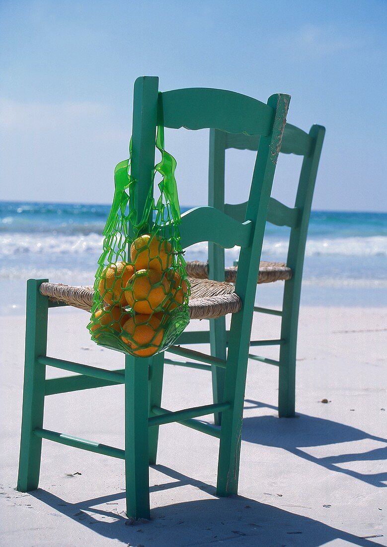 Zwei Stühle mit Orangen am Strand