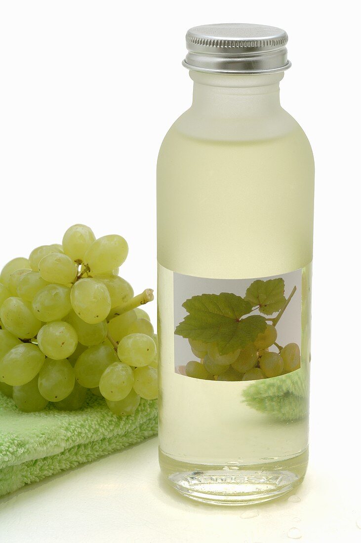 White grape seed oil and white grapes on towel