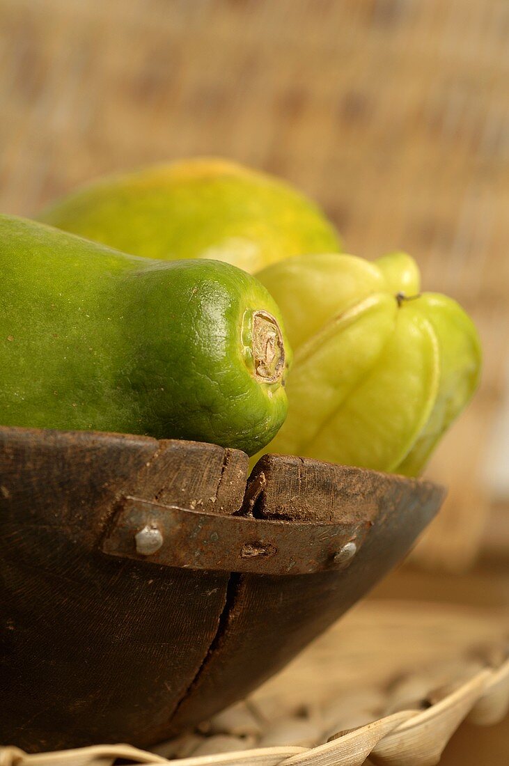 Exotische Früchte in Holzschale (Papaya, Karambole, Mango)