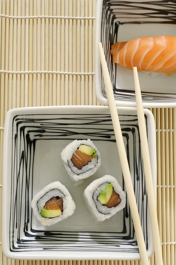 Drei Maki-Sushi und ein Nigiri-Sushi in viereckigen Schalen