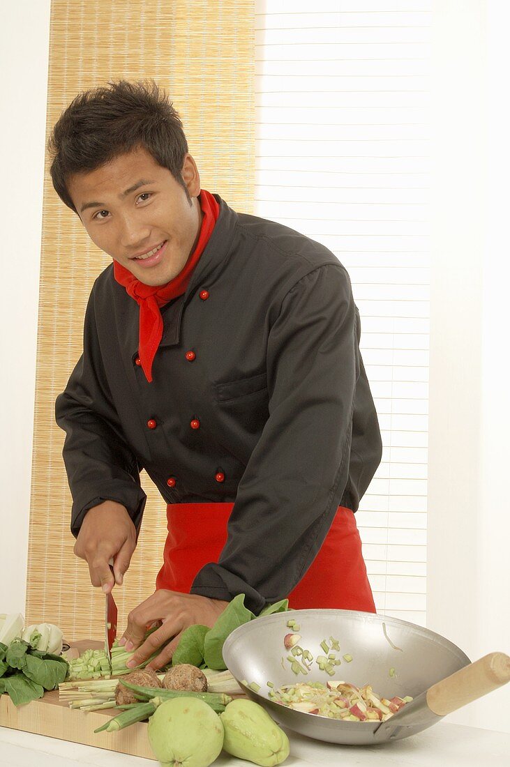Asiatischer Koch bereitet Gemüse für Wokgericht zu