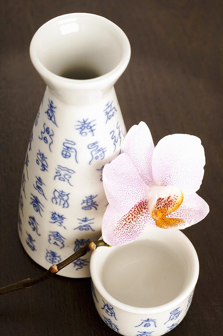 Sakeflasche (Choshi) und Sakebecher (Sakazuki) mit Orchidee