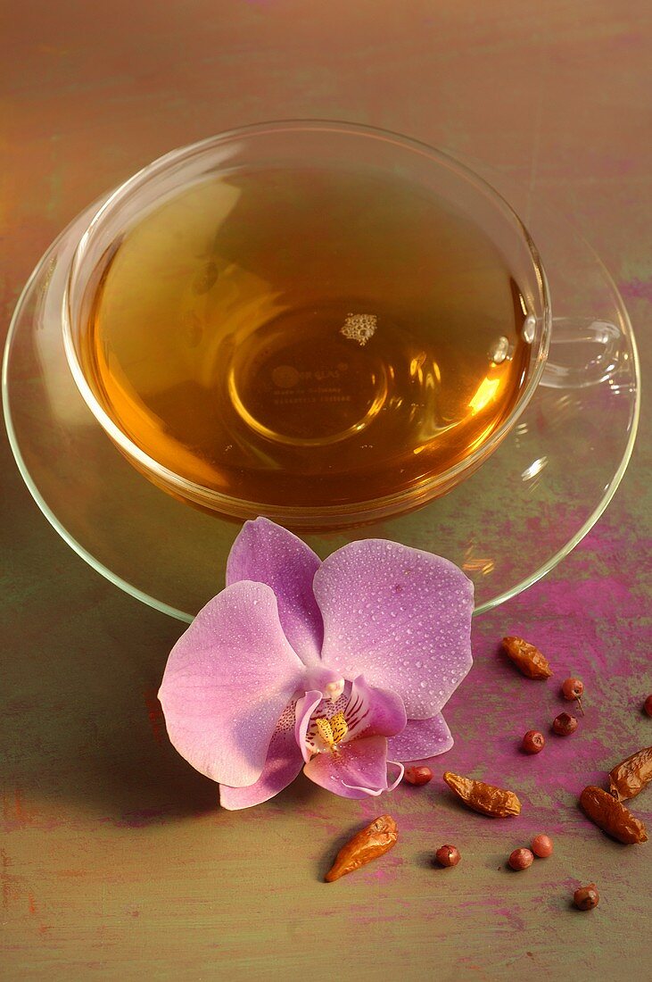 Tee mit getrockneten Chilischoten und Orchideenblüte