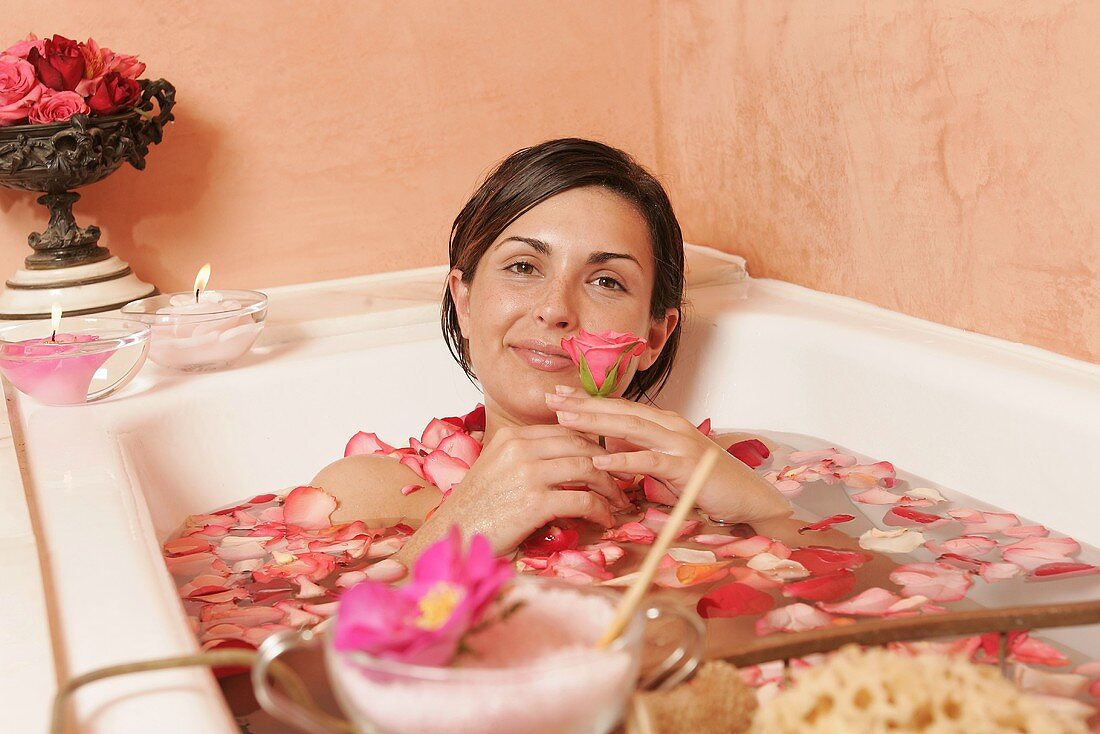 Junge Frau in der Badewanne mit Blütenblättern