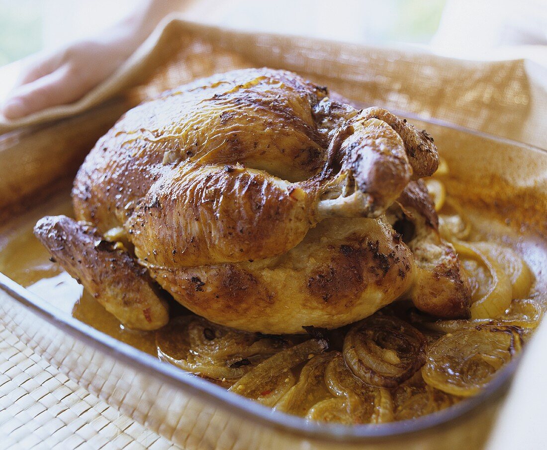 Stuffed chicken with onions in roasting tin