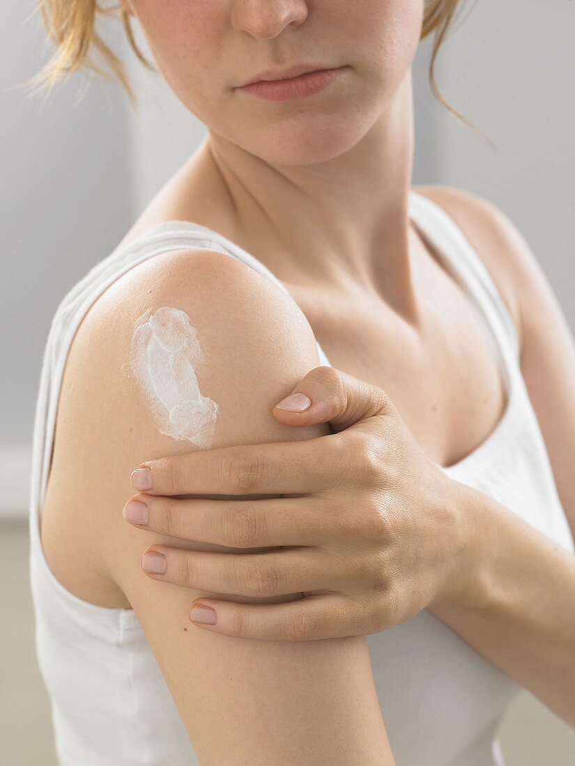 Woman putting cream on her shoulder