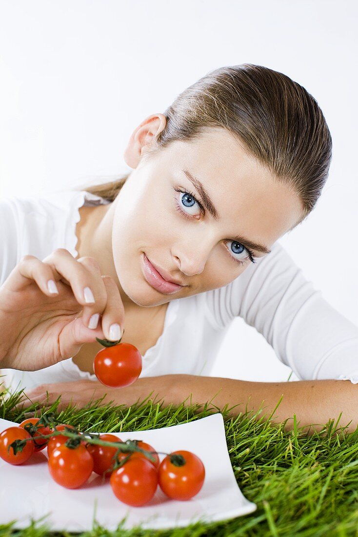 Young woman holding a cocktail tomato in her hand