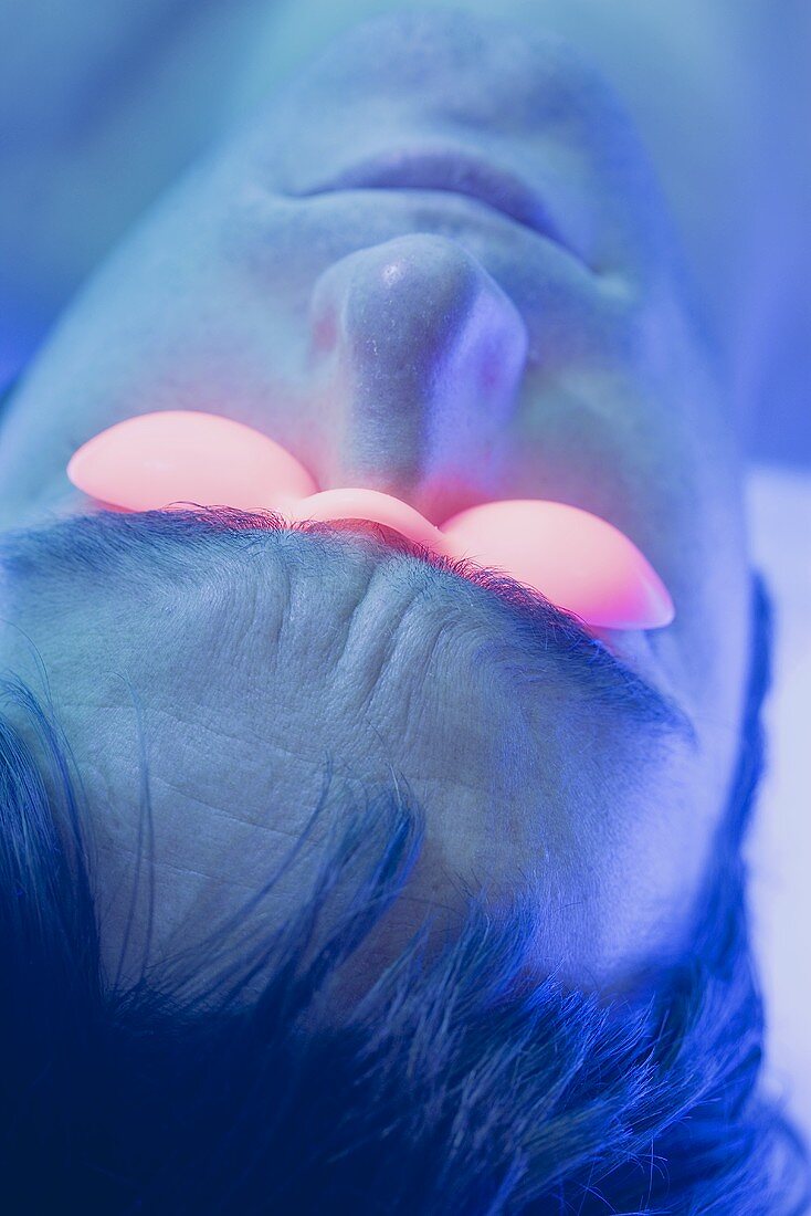 Young man in tanning goggles on tanning bed (close-up)