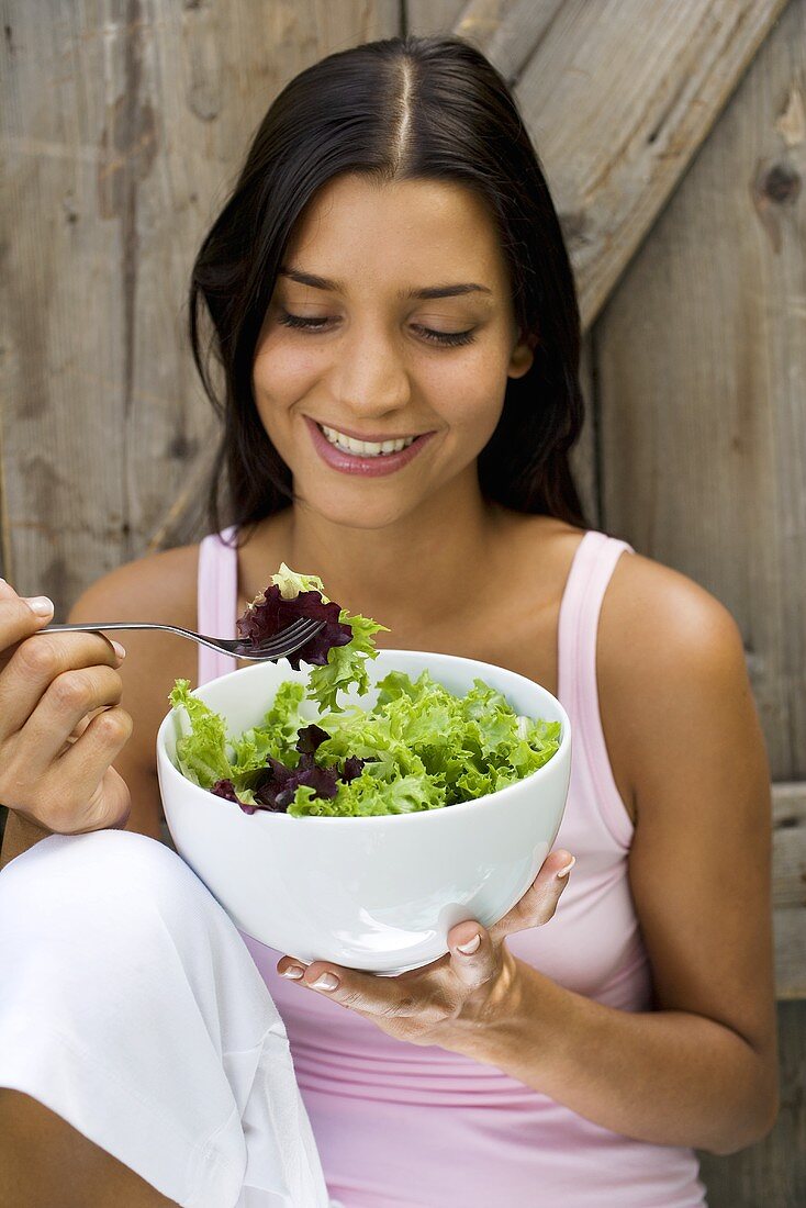 Young woman eating green salad