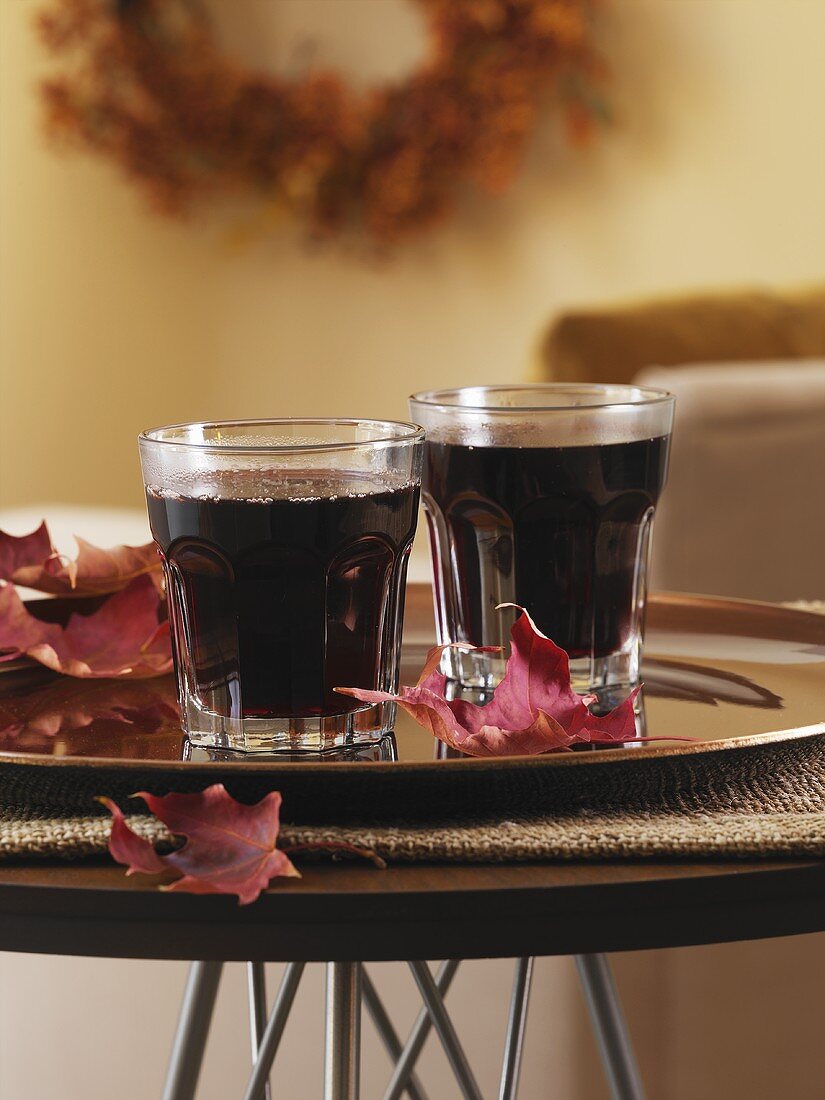 Mulled wine in two glasses and maple leaves on tray