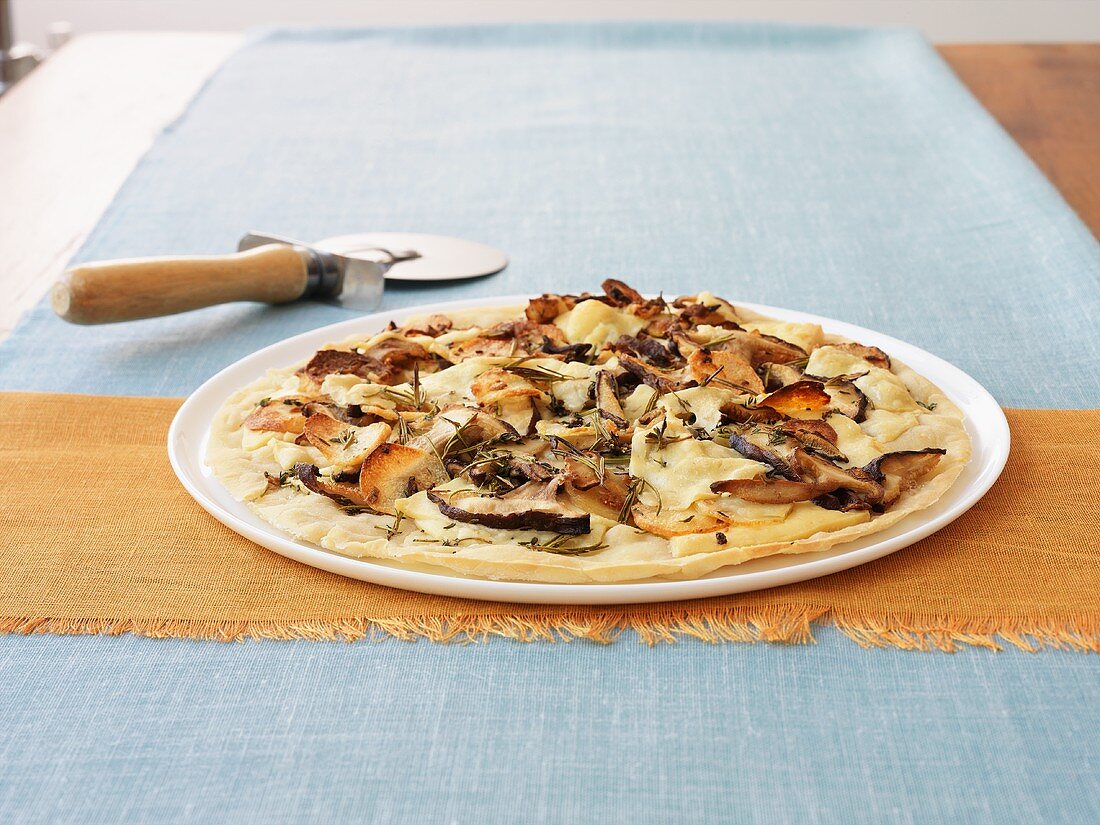 Potato pizza topped with shiitake mushrooms, pizza cutter